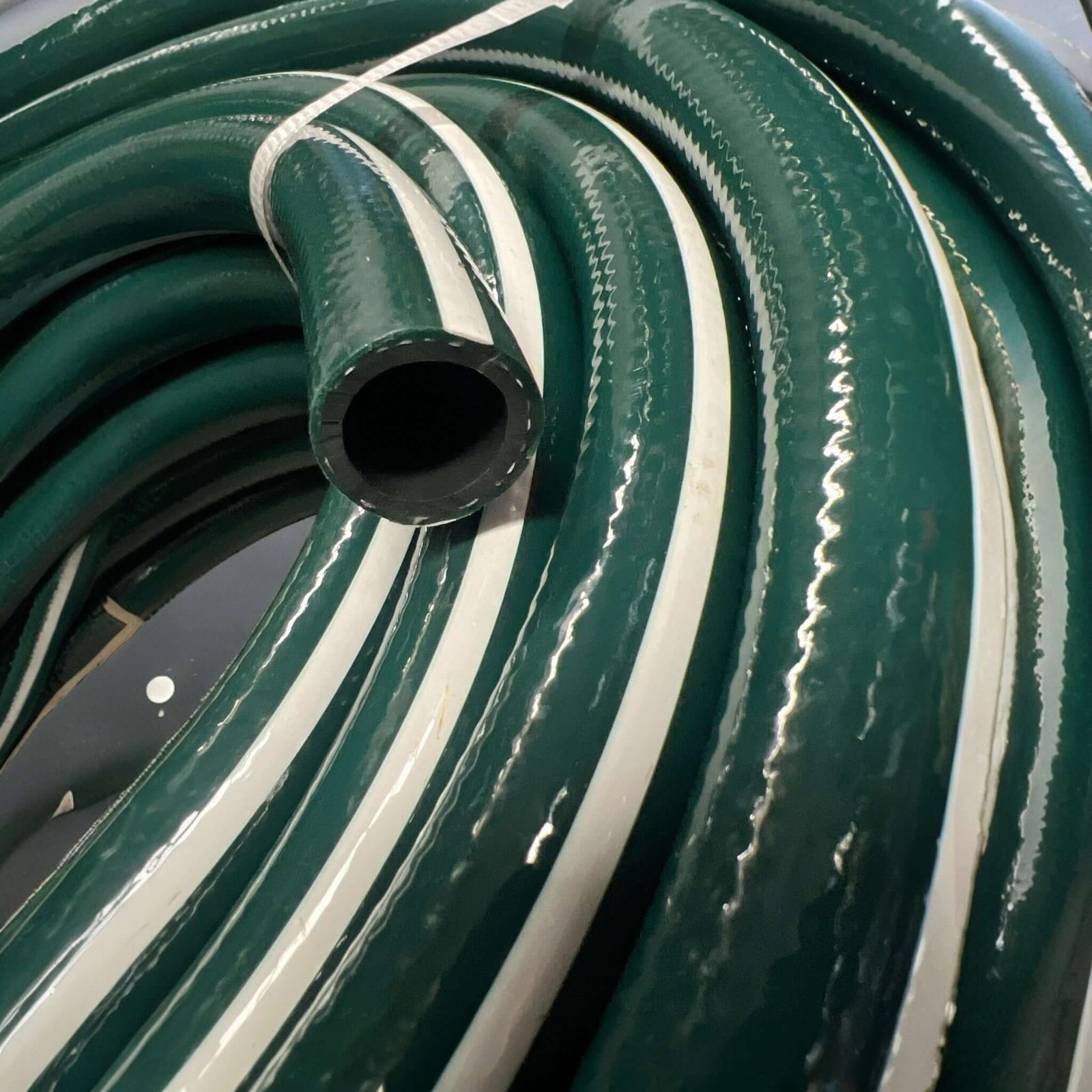 Premium Garden Hose 18mm Thick Braided UV Anti Kink Clearance coiled with dark green and white stripes.